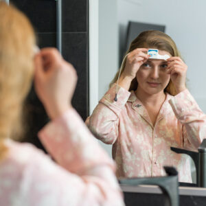 Patientin platziert Home Sleep Test an ihrem Stirn, Spiegelbild
